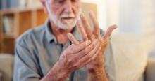 Een man met reumatoïde artritis pakt met zijn ene hand zijn andere vast