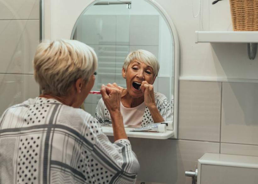 vrouw met mondproblemen in de laatste fase van haar leven poetst tanden