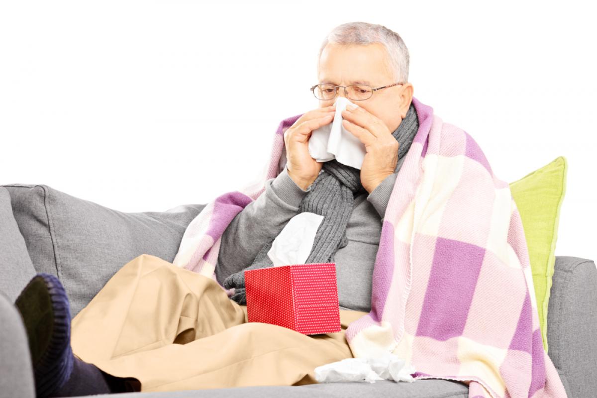 man met griep en snuitend in tissue