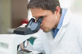 Een laborant onderzoekt cellen of een stukje weefsel onder de microscoop