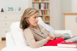 Vrouw zit op de bank en kijkt voor zich uit