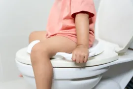 Een kind met blaasontsteking zit op de wc